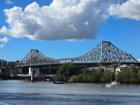 The Story Bridge spanning the Brisbane River under a blue sky with white cloud