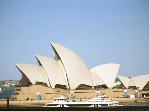 The Sydney Opera House across the harbour on a clear day, with a ferry passing in front