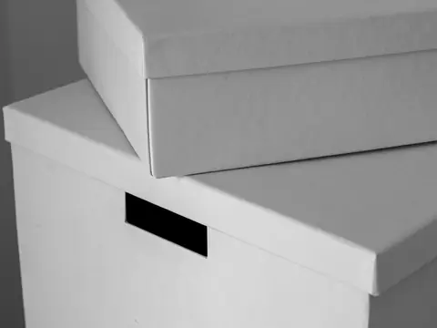 Two plain white storage boxes stacked one on the other, close up